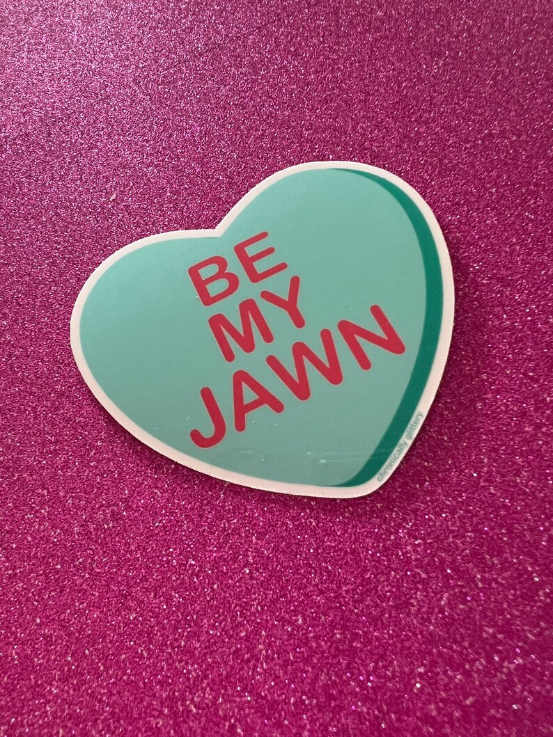 May include: A teal heart-shaped sticker with the text "BE MY JAWN" in red letters.