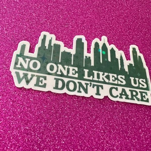 May include: A green and white sticker with a city skyline and the text "NO ONE LIKES US WE DON'T CARE".