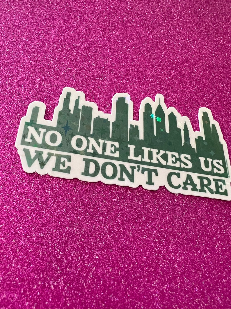 May include: A green and white sticker with a city skyline and the text "NO ONE LIKES US WE DON'T CARE".