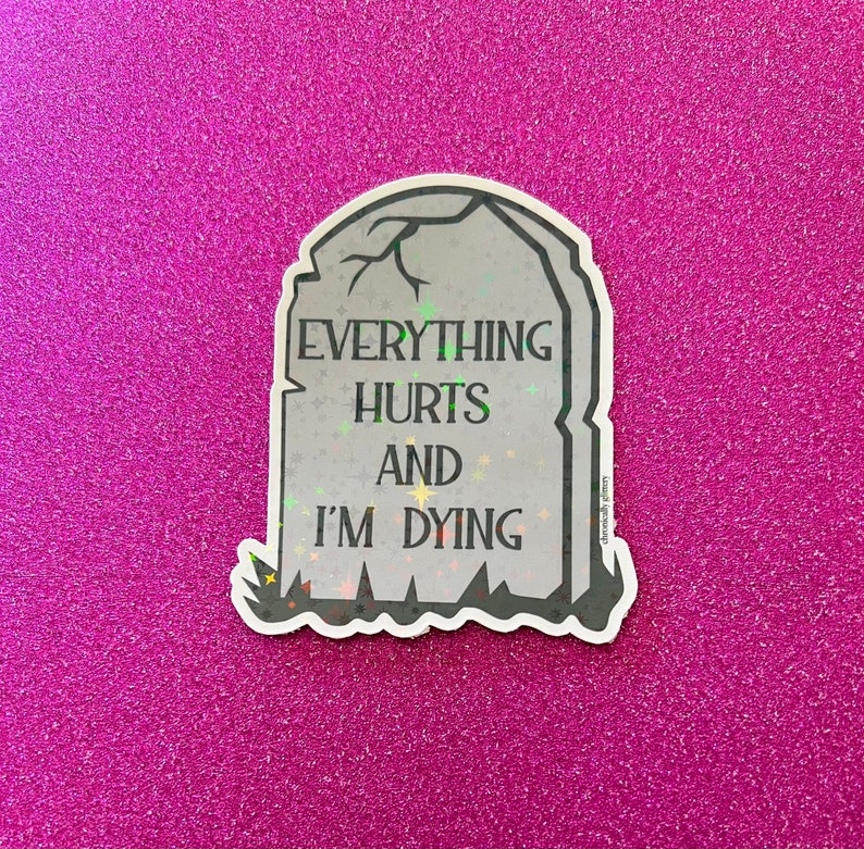 May include: A white sticker with a gray tombstone design. The tombstone has the text "Everything Hurts And I'm Dying" on it.