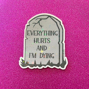 May include: A gray tombstone sticker with a glittery finish. The sticker reads "Everything Hurts And I'm Dying".