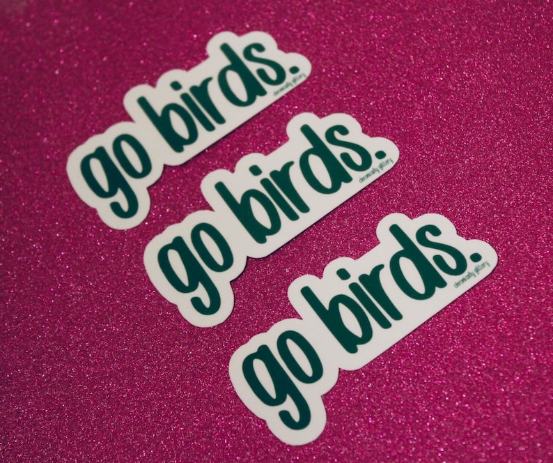 May include: Three white stickers with the text "go birds." in dark green lettering on a pink sparkly background.