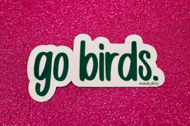 May include: Green "go birds" sticker on a pink glitter background.