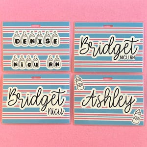 May include: Four name badge holders with a blue and pink striped background. The badges feature names like "Denise", "Bridget", and "Ashley" in a cursive font. Some badges include baby bottle graphics and the text "NICU RN".