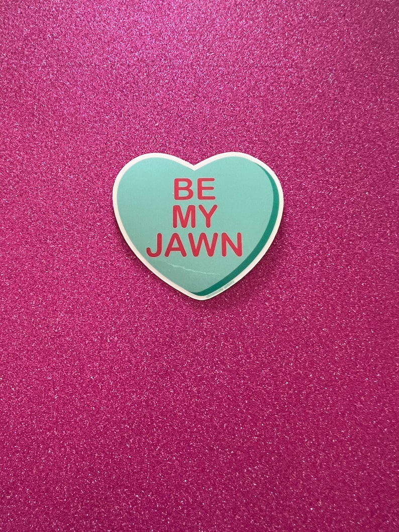 May include: A light blue heart-shaped sticker with the text "BE MY JAWN" in red letters on a pink glitter background.