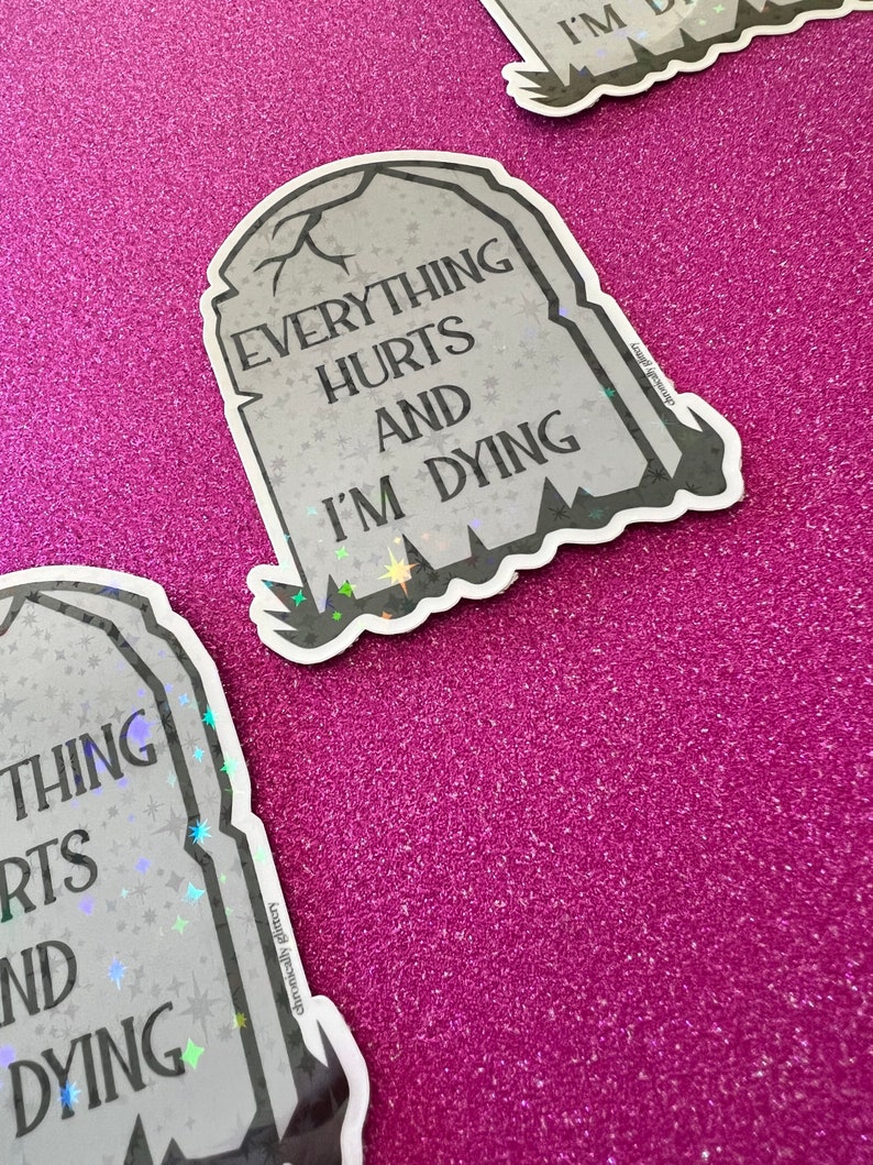 May include: A gray tombstone sticker with the text "Everything Hurts And I'm Dying" in black lettering. The sticker has a glittery finish and a black outline.