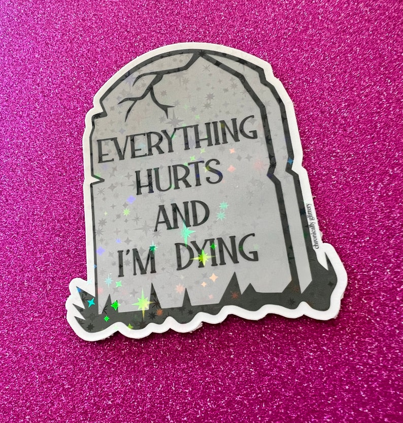 May include: A white and gray holographic sticker with a tombstone shape. The sticker has the text "Everything Hurts And I'm Dying" on it.