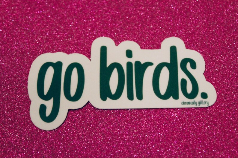 May include: White sticker with the text "go birds." in dark green lettering. The sticker has a white border and a small, dark green "chronically glittery" text at the bottom.