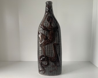 Puede incluir: Un jarrón de cerámica marrón con un patrón geométrico y un diseño en relieve de una persona montando un pájaro.