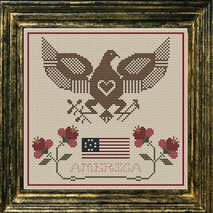 May include: A cross-stitch pattern featuring an American bald eagle with a heart in its chest, a flag with 13 stars, and the word "AMERICA" below. The eagle is brown and the flag is red, white, and blue.