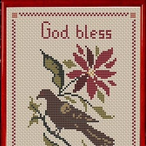 Puede incluir: Obra de arte de punto de cruz en un marco rojo. El diseño presenta un pájaro marrón posado en una rama con una flor roja y las palabras "God bless America". El fondo es de color crema.