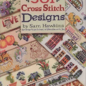 May include: A book titled "501 Cross Stitch Designs" by Sam Hawkins for American School of Needlework, Inc. The cover features a variety of cross stitch designs, including a train, a duck, a house, a dog, a cat, a flower, and a pumpkin.