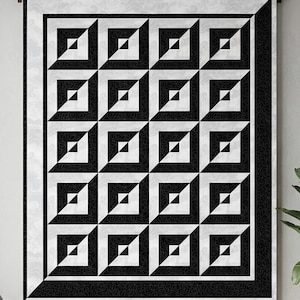 May include: A rectangular quilt featuring a repeating geometric pattern of black and white squares arranged in a grid. Each square contains a smaller triangle motif, creating a three-dimensional effect. The quilt has a wide black border with a subtle pattern and a thin white outer frame.