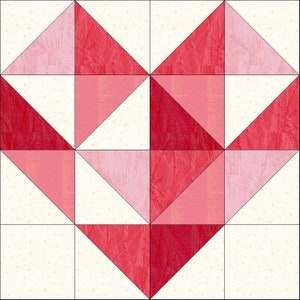 Op de afbeelding: Een quiltblok met een hartvormig ontwerp gemaakt van rode, roze en witte stof. Het hart is gemaakt van driehoeken en vierkanten.