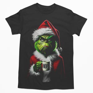 May include: A black t-shirt featuring a green Grinch wearing a Santa hat and holding a mug that says "NOPE".