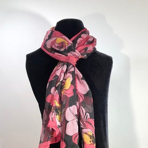 An elegant super sheer silken chiffon scarf of pinks, rasberry red, yellow flowers on a field of solid black, bordered in reddish pink.