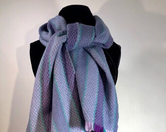 A purple, lilac and grey striped soft, warm scarf nicely accented with thin strips of contrasting greenish turquoise.