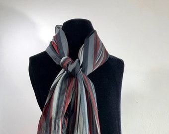 A sheer and blacks with a solid black border. feathery light stylishly striped scarf of cranberry red shades of grays