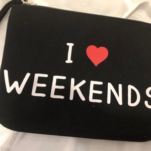 A black canvas clutch with a bold &quot;I love (red heart) weekends&quot; emblazoned on the front. Fun & practical!