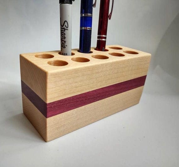 Handcrafted from contrasting Maple and Purple Heart hardwoods with 10 precision-drilled holes — the kind of heirloom desk piece a serious pen collector would actually brag about.