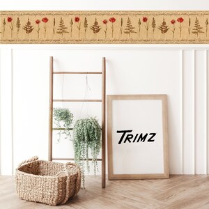 May include: A wooden ladder leaning against a white wall with a framed print that says "Trimz" hanging above a woven basket. Two hanging plants are in front of the ladder.