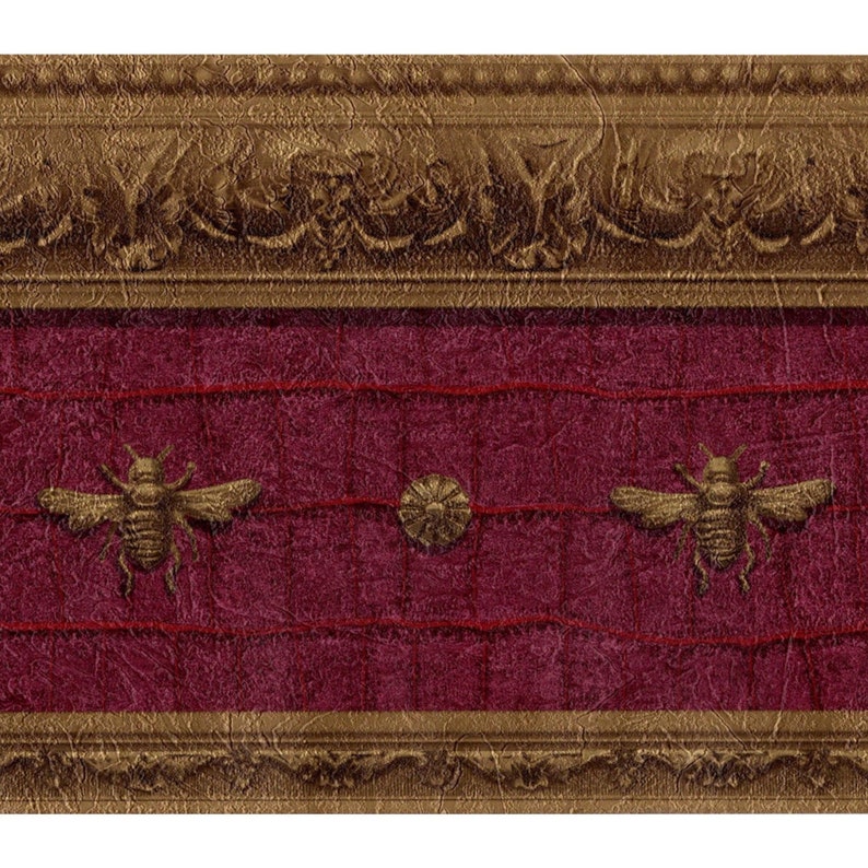 Raymond Waites Napoleonic Bee wallpaper border in maroon and burnished gold, featuring gold bees and medallions on a textured faux leather background.