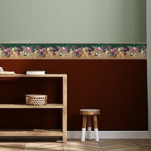 Puede incluir: Una estanter&iacute;a de madera con dos estantes, una cesta tejida en el estante superior y un peque&ntilde;o taburete de madera delante. La pared detr&aacute;s de la estanter&iacute;a est&aacute; pintada de color marr&oacute;n oscuro y tiene un borde decorativo con un dise&ntilde;o floral en tonos verdes, rosas y dorados.