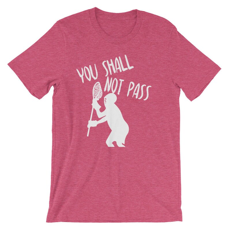 May include: A pink t-shirt with the text "You Shall Not Pass" in white lettering. A white silhouette of a person holding a lacrosse stick is below the text.