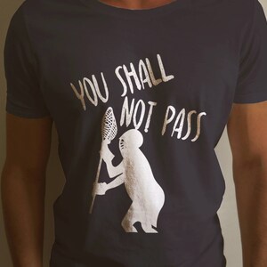 May include: A black t-shirt with white text that reads "You Shall Not Pass" and a white silhouette of a person holding a lacrosse stick.