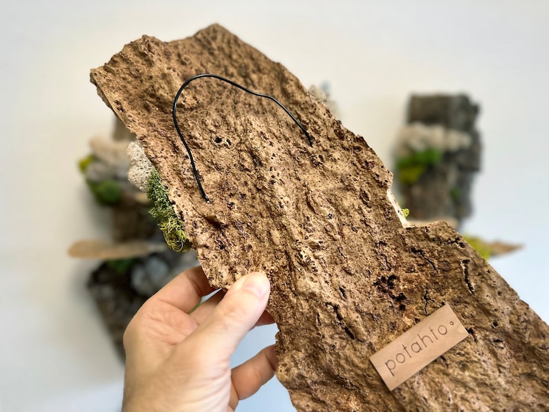May include: A brown, textured, rock-like wall hanging with a black wire hanger and a small brown tag that says "potahto."