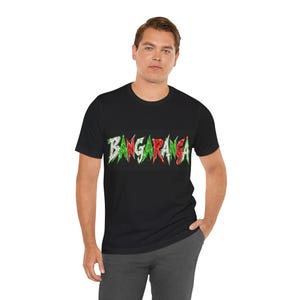 Könnte beinhalten: Schwarzes T-Shirt mit dem Wort "BANGARANGA" in Grün und Rot, stilisiert mit einer gezackten, verwitterten Schriftart. Das T-Shirt hat einen Rundhalsausschnitt.