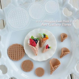 May include: A silicone mould for making miniature waffle cones and waffle rounds. The mould is clear and has a grid pattern. The image also shows miniature waffle cones and rounds made with the mould, decorated with fruit and cream.