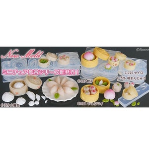 May include: A set of silicone moulds for making miniature Chinese dim sum, including a steamer basket, dumplings, buns, and a plate of dumplings. The moulds are clear and have a variety of shapes and sizes. The text on the moulds reads "New Mold" and "Miniature Chinese Dim Sum Series New Release!"