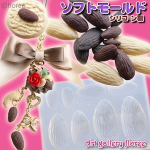 May include: A silicone mould for making almond-shaped chocolate sweets. The mould has nine cavities, each shaped like an almond. The mould is white and has the text "Art gallery floree" printed on it. There are also several chocolate almonds in the image, some are white and some are brown.