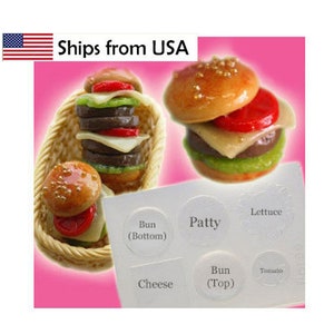 May include: Miniature burger food art with a bun, patty, cheese, tomato, and lettuce. The burger is in a woven basket. A clear plastic mold with labels for burger ingredients is also shown.