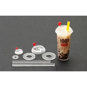 May include: A set of clear plastic lids for bubble tea cups, including a straw, and a cup with a lid and a red and yellow straw. The cup has the text "100% Taiwan" printed on it.