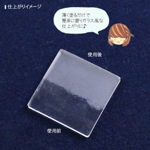 May include: A clear, square-shaped object with a frosted appearance on one half, demonstrating a before-and-after effect. Japanese text and a cartoon illustration are present, with the text indicating the product's effect.