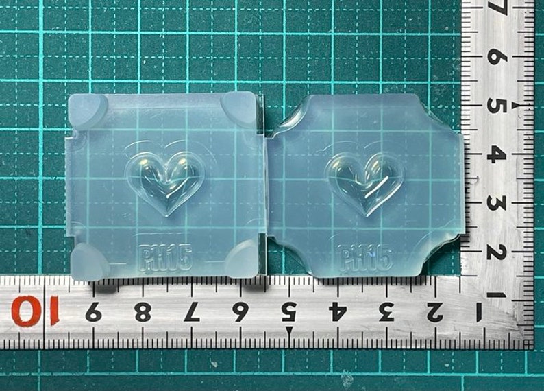 May include: Two clear silicone molds with a heart shape design. The molds are labeled "PH15".