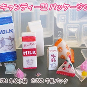 Puede incluir: Un conjunto de moldes de pl&aacute;stico transparente para hacer dulces en miniatura, cartones de leche y bolsas. Los moldes est&aacute;n etiquetados con el texto japon&eacute;s "C-781", "C-782", "C-783" y "C-784". Los moldes est&aacute;n rodeados de dulces en miniatura, cartones de leche y bolsas hechos con los moldes.