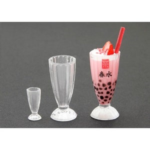 May include: Three clear plastic cups, one with a pink drink with black boba balls and a strawberry on top. The drink has a label that says "春水" in Chinese characters.