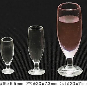 May include: Three clear glass champagne flutes of different sizes. The smallest flute is 15 mm in diameter and 5.5 mm tall. The middle flute is 20 mm in diameter and 7.3 mm tall. The largest flute is 30 mm in diameter and 11 mm tall.