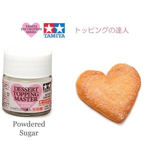 May include: A small white bottle of Tamiya Dessert Topping Master powdered sugar. The bottle has a pink heart with the text "Dessert Topping Master" and "Powdered Sugar" in black. The bottle is labeled "トッピングの達人" in Japanese, which translates to "Topping Master".