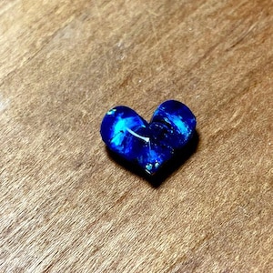 May include: A blue heart-shaped resin piece with white swirls and glitter.