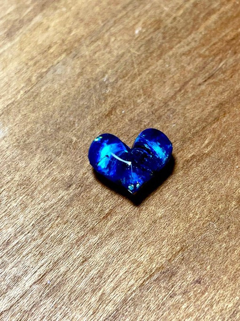 May include: A blue heart-shaped resin piece with white swirls and glitter.