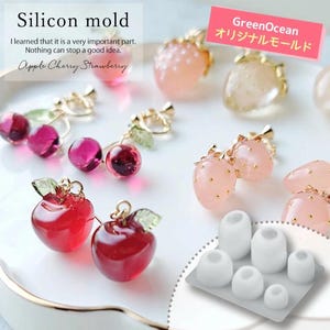 May include: A silicone mould for making fruit-shaped earrings. The mould has six cavities, each shaped like a different fruit: an apple, a cherry, and four strawberries. The mould is white and has a smooth surface. The image also shows examples of earrings made with the mould, including red apple earrings, red cherry earrings, and pink strawberry earrings.