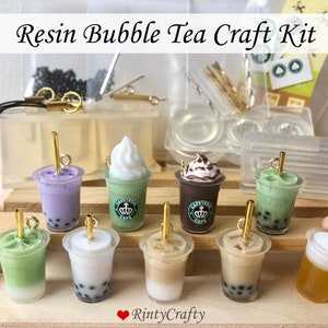 Könnte beinhalten: Ein Harz-Bubble-Tea-Bastelset mit acht verschiedenen Bubble-Tea-Anhängern. Die Anhänger sind aus klarem Harz gefertigt und zeigen verschiedene Bubble-Tea-Geschmacksrichtungen, darunter Milchtee, Taro, Matcha und Schokolade. Das Set enthält außerdem eine Vielzahl von Werkzeugen und Materialien zum Herstellen der Anhänger, wie z. B. Formen, Harz und Glitzer.