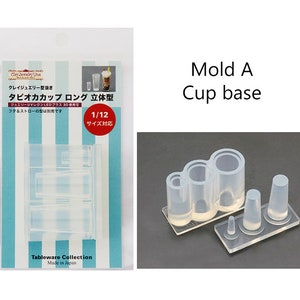 May include: Clear silicone mold for making miniature cup bases. The mold is designed to create three different sizes of cup bases. The mold is labeled "Mold A Cup base 1/12 Size".