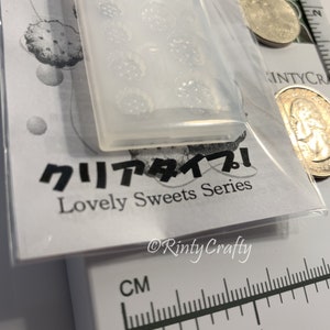 Pu&ograve; includere: Uno stampo in silicone trasparente con un design di diversi piccoli fiori. Lo stampo &egrave; su una superficie bianca con testo giapponese che recita "Tipo chiaro! Serie di dolci deliziosi" e "Rinty Crafty".
