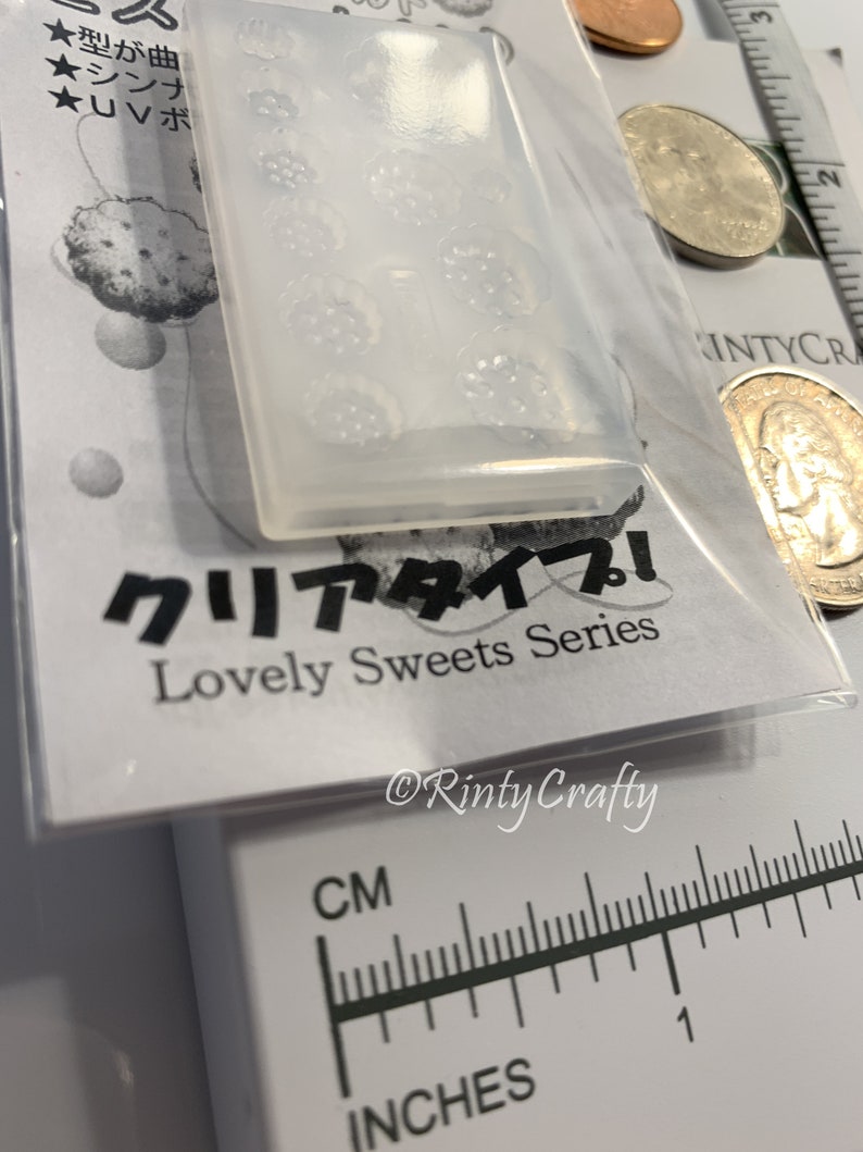 Pu&ograve; includere: Uno stampo in silicone trasparente con un design di diversi piccoli fiori. Lo stampo &egrave; su una superficie bianca con testo giapponese che recita "Tipo chiaro! Serie di dolci deliziosi" e "Rinty Crafty".