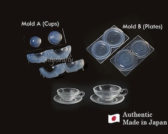 May include: Two clear silicone molds for making miniature cups and plates. The mold for cups has two individual cups and two sets of handles. The mold for plates has two individual plates. The molds are labeled "Mold A (Cups)" and "Mold B (Plates)".